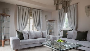 Ein modernes Wohnzimmer mit einem Ecksofa, einem Glastisch und einer Chandelier.