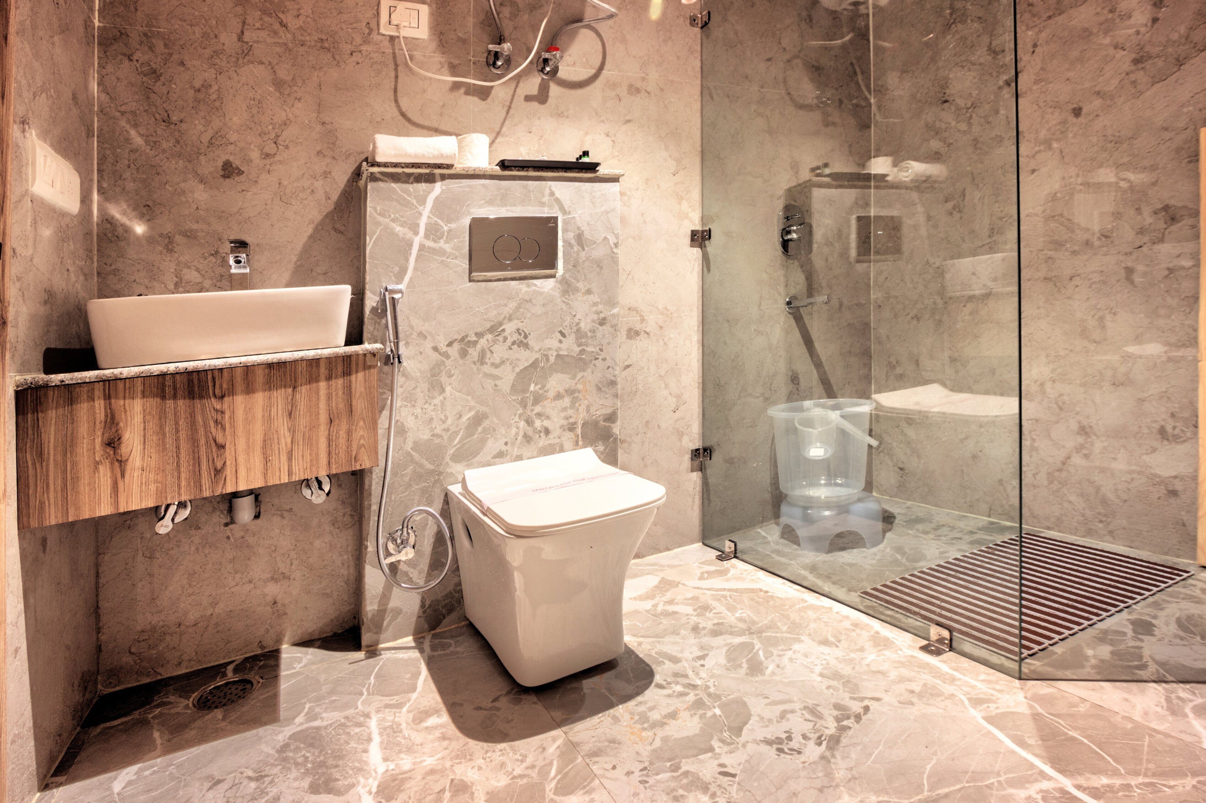 A modern bathroom with a marble sink, wooden vanity, and a glass shower enclosure.