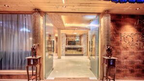 A reception area with a wooden wall, a reception desk, and a glass door. - Katson Courtyard Mashobra (Shimla)