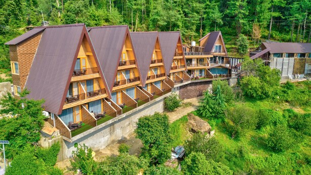 A row of wooden cabins with sloped roofs, set in a forested area. - Katson Courtyard Mashobra (Shimla)