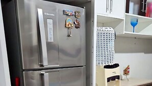 Eine Küche mit einem Edelstahl-Kühlschrank, einer Mikrowelle und einem kleinen Backofen.