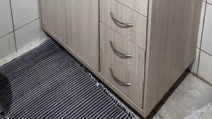 Ein Badezimmer mit weißen Fliesen, einer Granit-Arbeitsplatte, einem Waschbecken, einem Spiegel und einem Handtuchhalter.