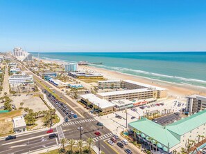An aerial view of a coastal city with a beach, roads, and buildings. - Coastal Condo Steps to Beach & Attractions (Daytona Beach)
