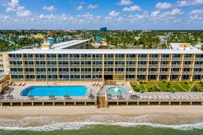 A hotel with a large pool, multiple balconies, and a view of the beach. - Coastal Condo Steps to Beach & Attractions (Daytona Beach)