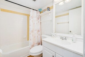 A bathroom with a bathtub, toilet, sink, and mirror. - Ocean View Condo | Beachfront Resort Escape (Daytona Beach)