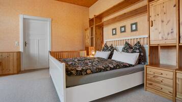 A bedroom with a bed, wooden headboard, a nightstand, a dresser, and a door.