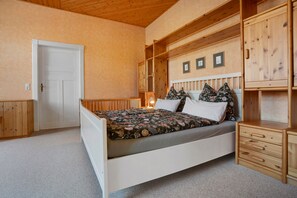 A bedroom with a bed, wooden headboard, a nightstand, a dresser, and a door. - Holiday Home 'Ivenack Old School' with Private Terrace and Private Garden (Ivenack)