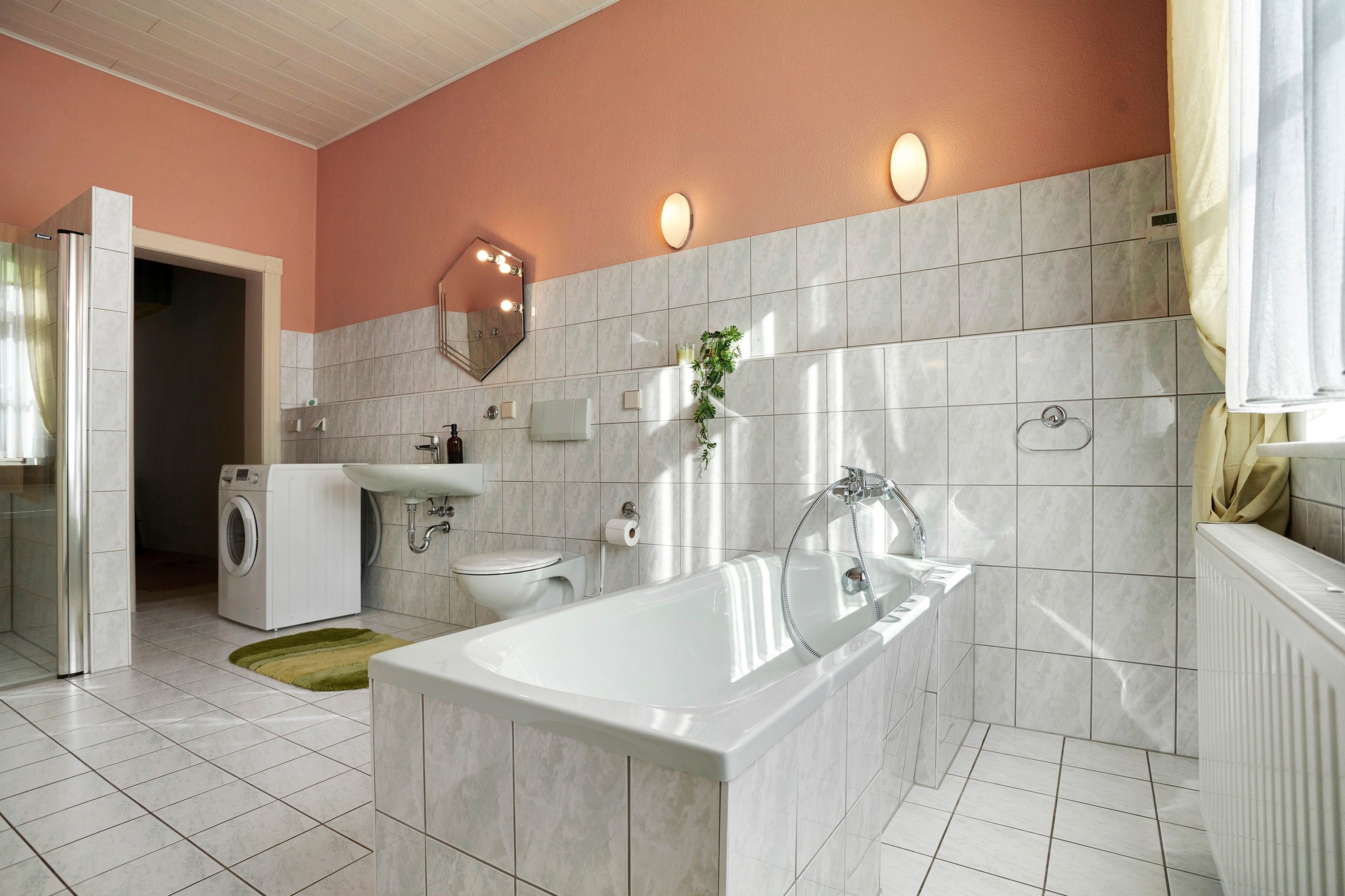 Ein modernes Badezimmer mit Badewanne, Toilette, Waschbecken und einer Waschmaschine.
