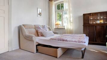 A bedroom with a bed, a chair, a cabinet, and a window with curtains.