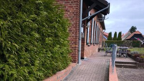 A brick pathway leading to a building with a metal railing and a bench. - Holiday Home 'Ivenack Old School' with Private Terrace and Private Garden (Ivenack)