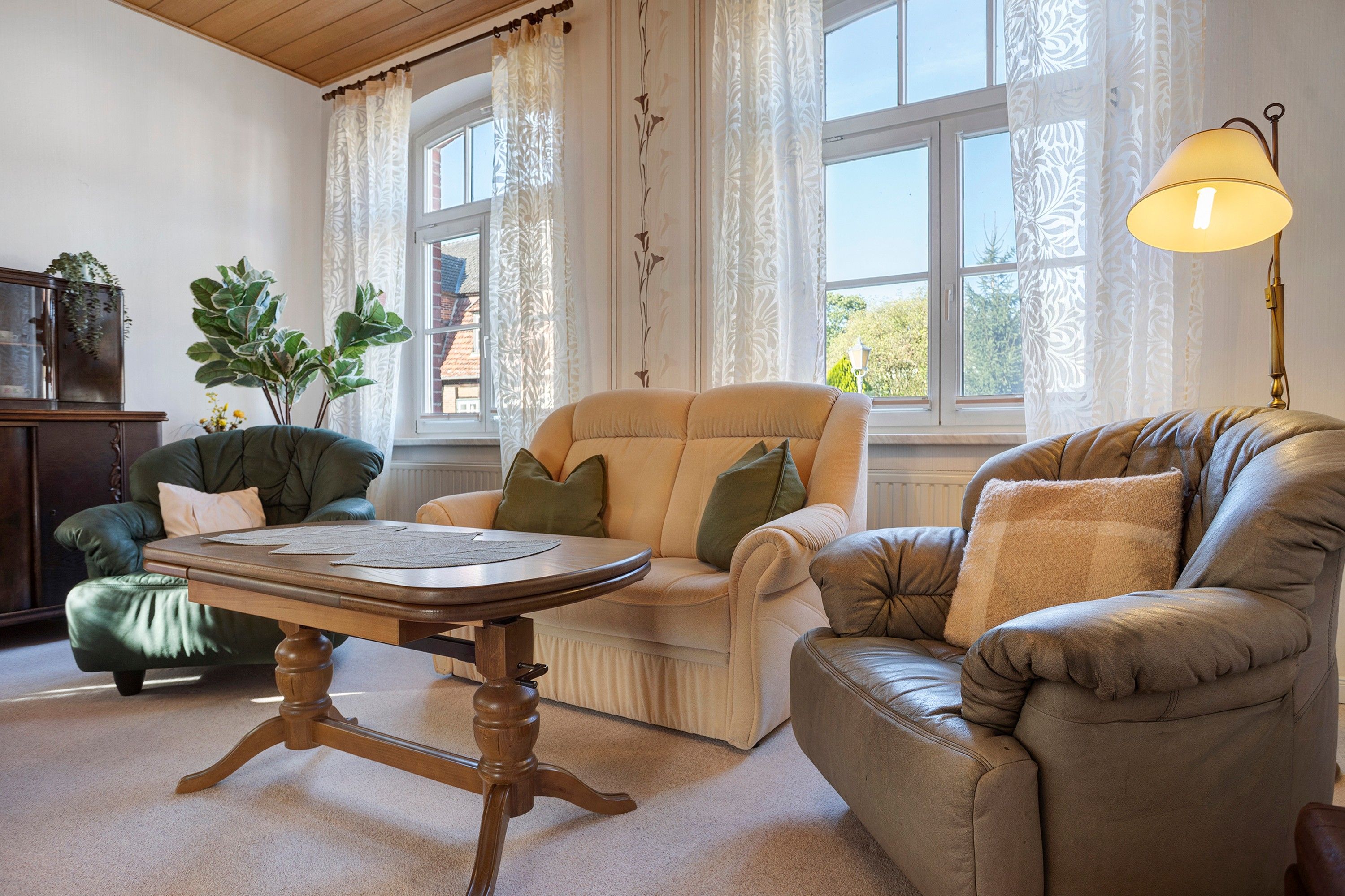 Un salon chaleureux avec une table en bois, deux fauteuils en cuir et un canapé.