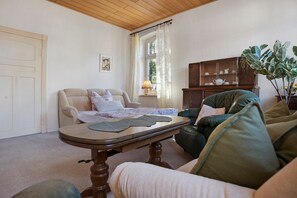 A living room with a sofa, a table, a cabinet, and a door. - Holiday Home 'Ivenack Old School' with Private Terrace and Private Garden (Ivenack)