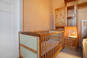 A wooden crib with a mattress, a nightstand with a lamp, and a wooden cabinet with drawers. - Holiday Home 'Ivenack Old School' with Private Terrace and Private Garden (Ivenack)