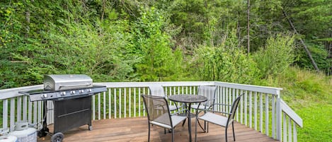 Een terras met een barbecue, een tafel en stoelen.