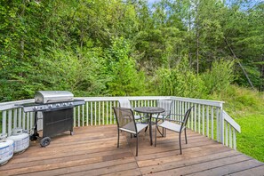 A deck with a barbecue grill, a table, and chairs.
