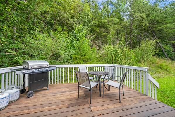 A deck with a barbecue grill, a table, and chairs.