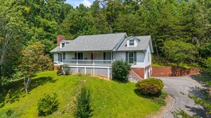 A two-story house with a front porch, surrounded by a well-maintained lawn and trees.