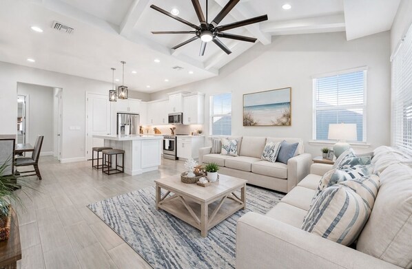 A spacious living area with a large sofa, a coffee table, and a kitchen in the background.