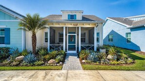 A two-story house with a covered porch, a number 7235, and a well-maintained garden with various plants. - Naples Luxury Cottage-Stylish 2BR in Premier Luxury Community (Naples)