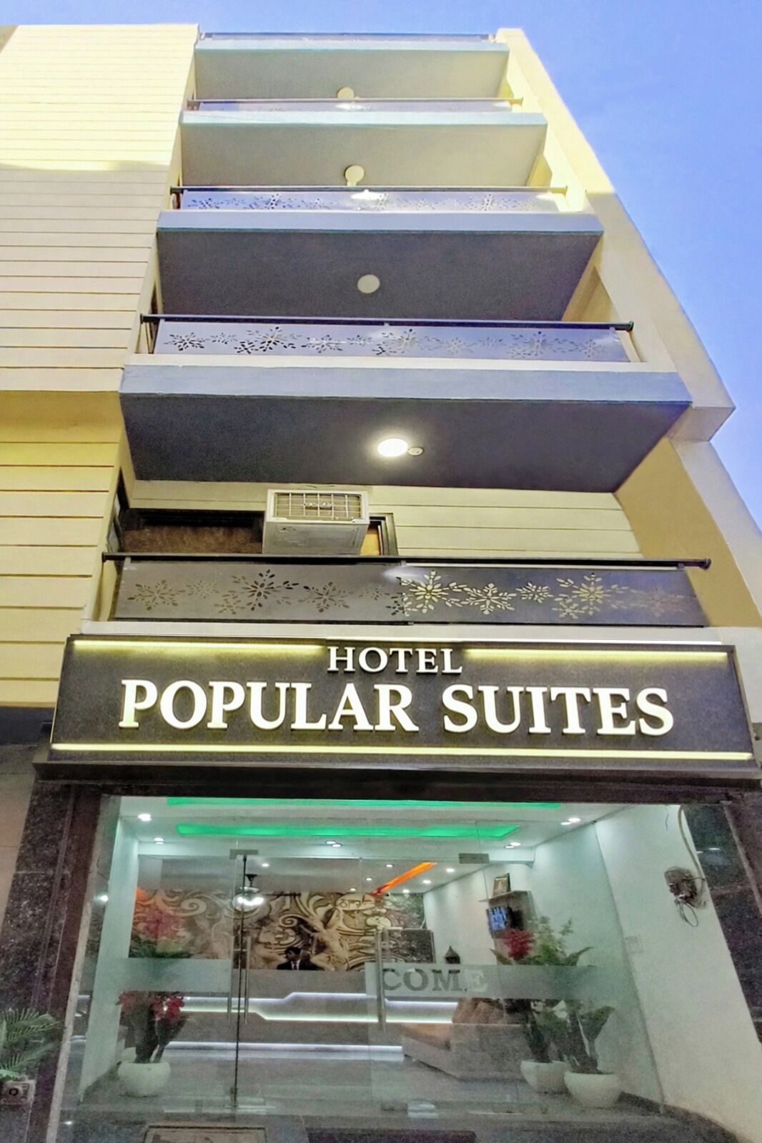 Een hotelentree met een bord waarop 'HOTEL POPULAR SUITES' staat.