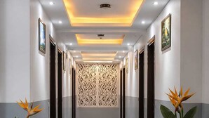 A hallway with a reflective floor, recessed lighting, and a decorative panel on the wall. - Hotel Popular Suites (New Delhi)