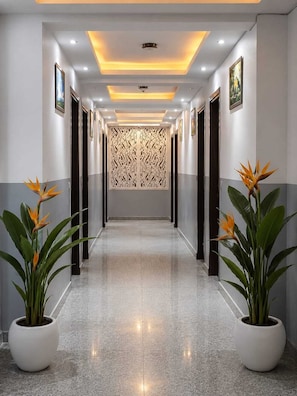 A hallway with a reflective floor, recessed lighting, and a decorative panel on the wall. - Hotel Popular Suites (New Delhi)