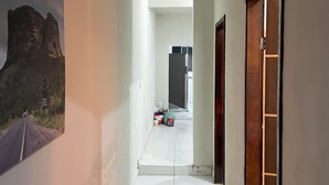 A hallway with a tiled floor, a door on the right, and a painting on the left. - Great value for money in Chapada! (Seabra)
