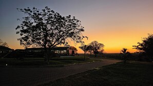 A building with a paved pathway and trees, set against a sunset sky. - Zebra Hilltop Lodge (Mazunga)