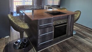 A modern kitchen with a central island, stainless steel appliances, and a large window. - Zebra Hilltop Lodge (Mazunga)