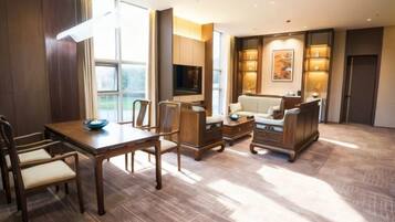 A spacious living area with a dining table, sofas, and a TV.