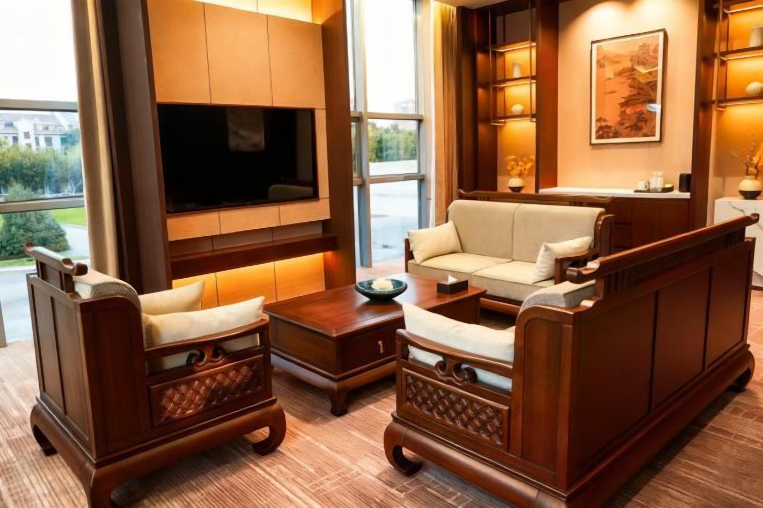 A modern living room with a flat-screen TV, comfortable seating, and a large window offering a view of the outdoors.