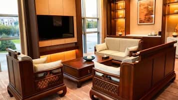 A modern living room with a flat-screen TV, comfortable seating, and a large window offering a view of the outdoors.