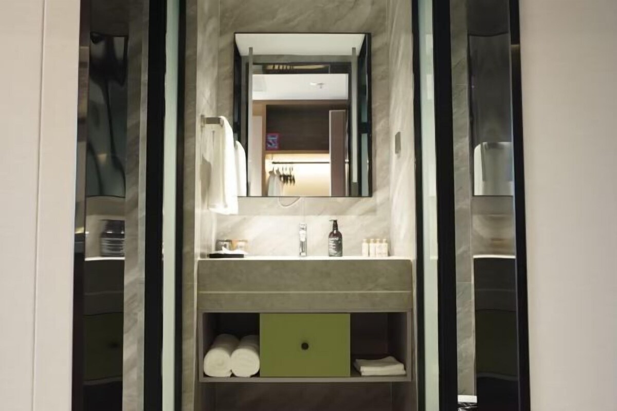 Un baño con espejo, lavabo y estantes de almacenamiento.