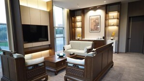 Una sala de estar moderna con un sofá, sillones, una mesita de centro, un televisor de pantalla plana y una chimenea.
