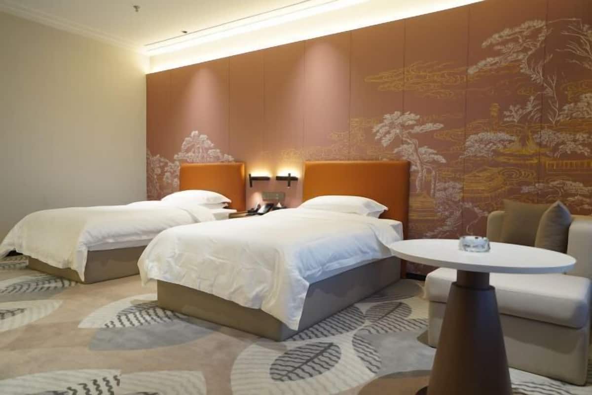 A hotel room with two beds, a round table, and a sofa.