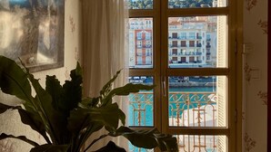 A room with a large window, a potted plant, and a framed picture on the wall.