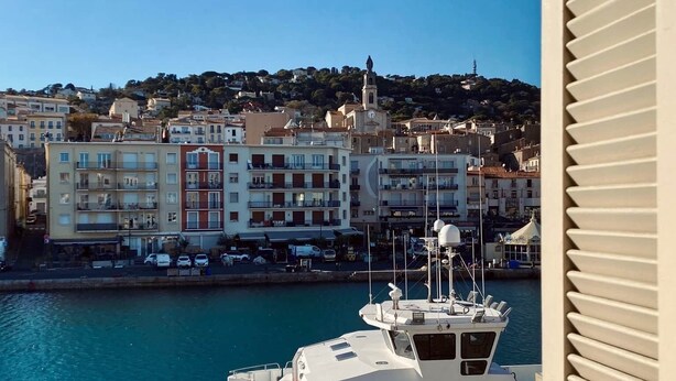 A coastal cityscape with buildings, a marina, and a boat named 'DEUX FRERES V'.