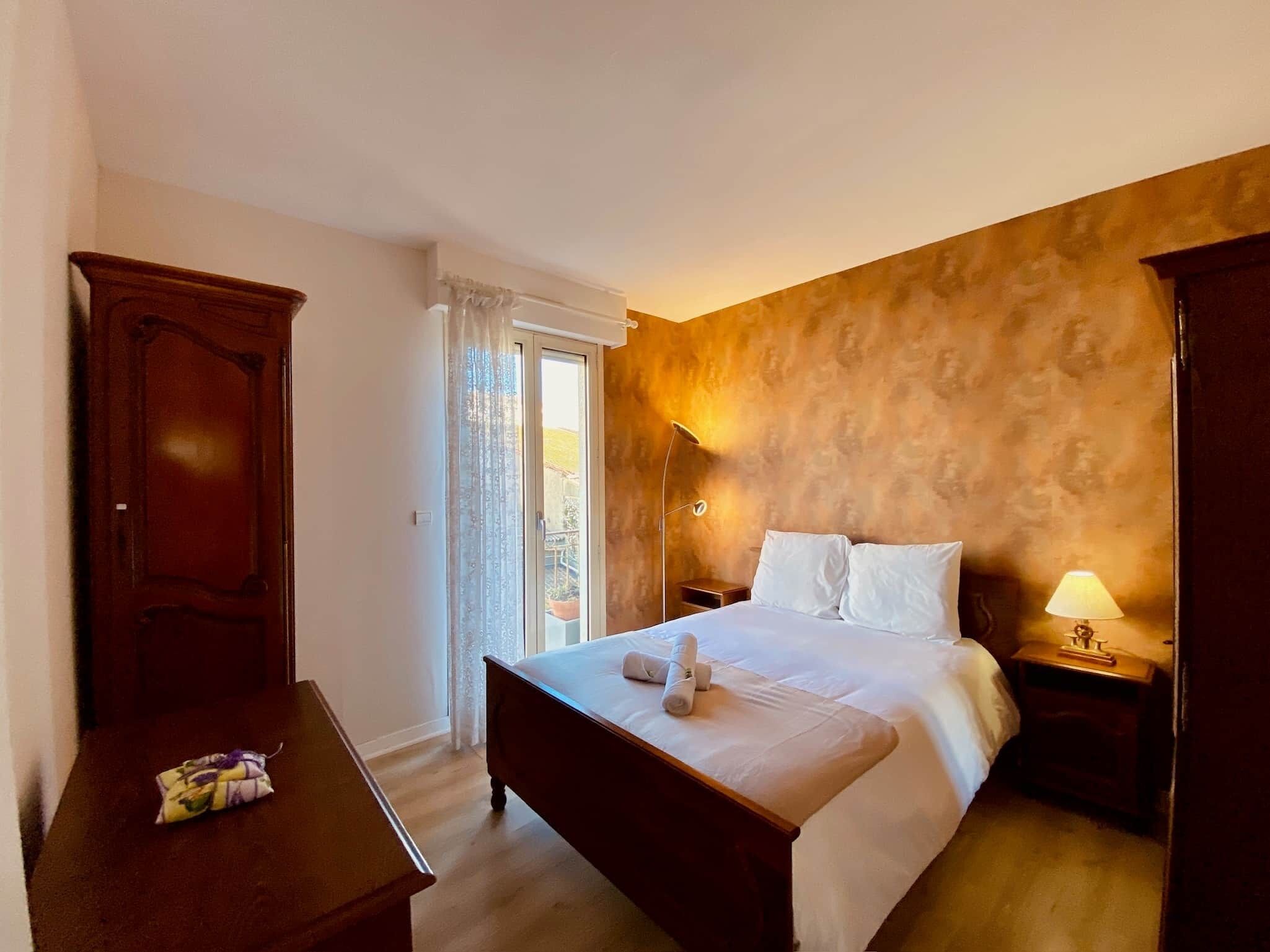 Ein Hotelzimmer mit Bett, Schreibtisch, Lampe und Blick ins Freie.