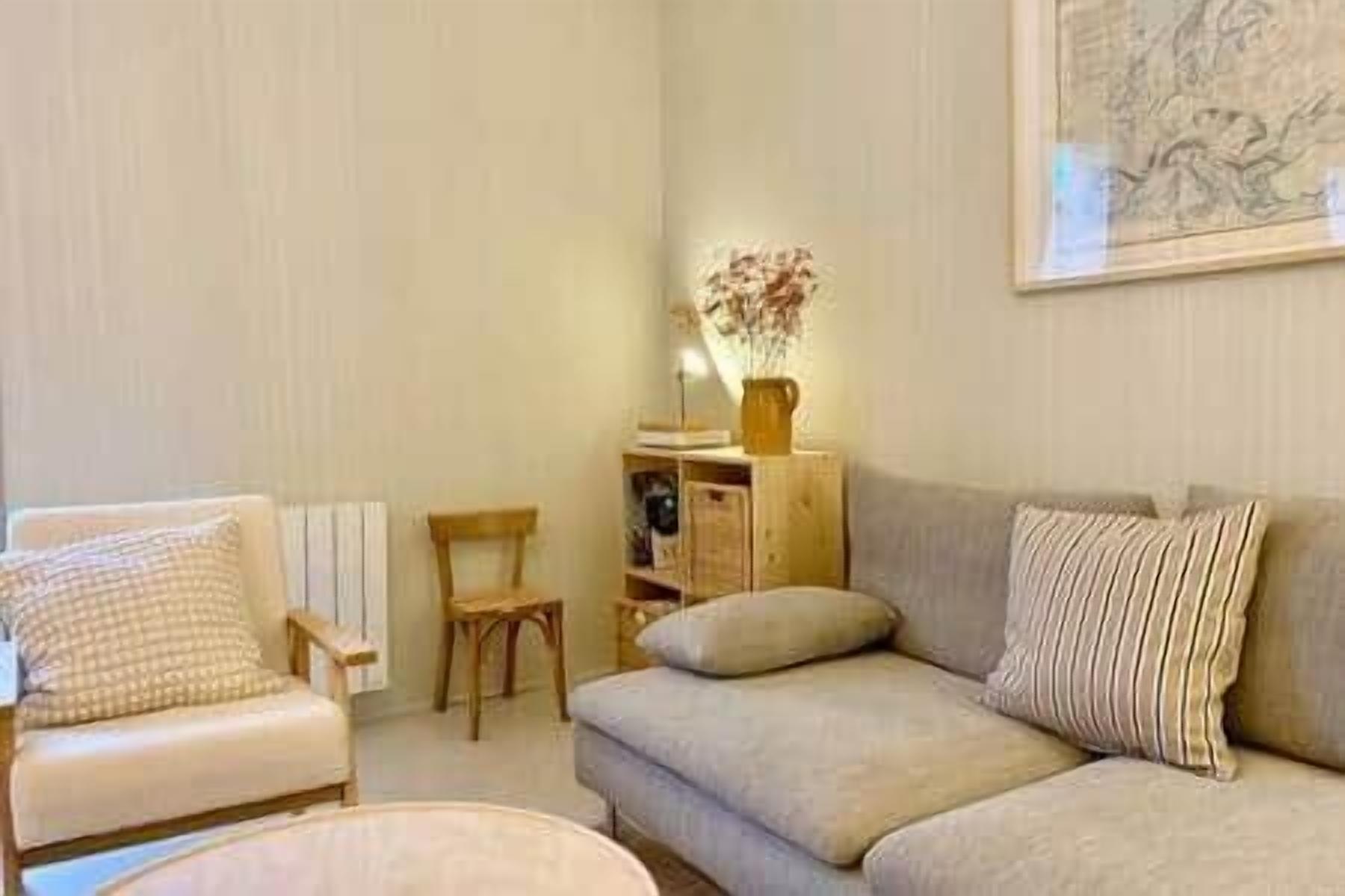 A living room with a sofa, a chair, a small table, and a bookshelf.