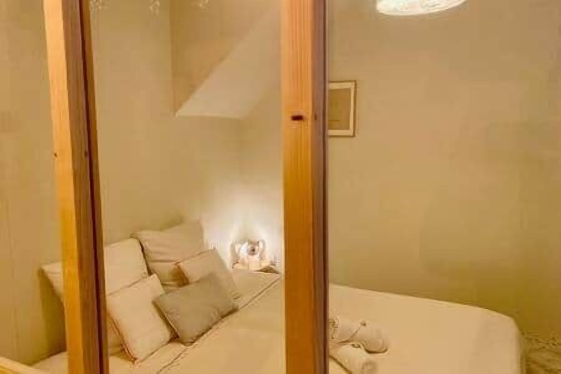 Une pièce comprenant un lit, une table de chevet et un luminaire fixé au mur.