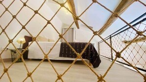 A bedroom with a bed, bedside table, lamp, and a view through a rope barrier. - "Suzon" Cosy little loft with terrace (Sète)