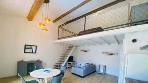 A modern interior with a dining area, a staircase to an upper level, and a kitchen. - "Suzon" Cosy little loft with terrace (Sète)