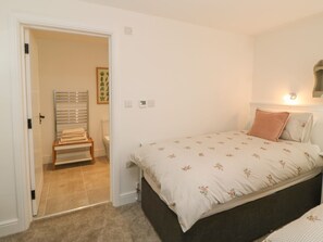 Ein Schlafzimmer mit einem Bett, einem Nachttisch, einer Wandleuchte und einer Tür zu einem Badezimmer.