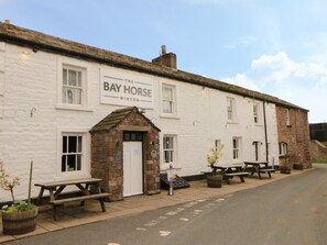 Ein weißes Gebäude mit einem Schild, auf dem 'The Bay Horse Winton' steht, und einem kleinen Backstein-Eingang.