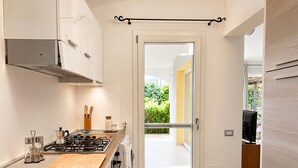 A modern kitchen with a gas stove, stainless steel sink, and a sliding glass door leading to a balcony.