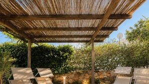A covered outdoor seating area with stone flooring and a wooden pergola. - Private villa 100 m from the sea, relaxation and privacy with Tavolara view (Pittulongu)