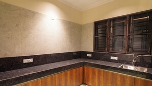 Una cocina con encimeras oscuras, armarios de madera, un lavamanos y un salpicadero de azulejos.
