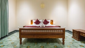 Una cama doble con estructura de madera, dos almohadas rojas y una colcha roja.