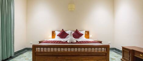 A double bed with a wooden frame, two red pillows, and a red blanket.