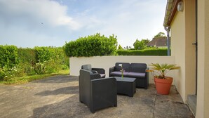An outdoor seating area with wicker furniture, a potted plant, and a view of the sky. - Holiday Home 'Gite De Pauline, Sainte-mère-église' with Private Terrace, Private Garden and Wi-Fi (Sainte-Mère-Église)